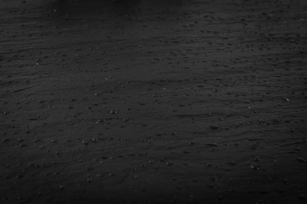 Wet black slate stone, food slate, slab surface, plate stone texture background. Chalkboard, graphite board, rock, slab rock pattern with water drops