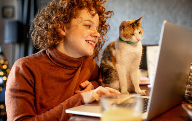 istock Young woman with cat using laptop 1217462491