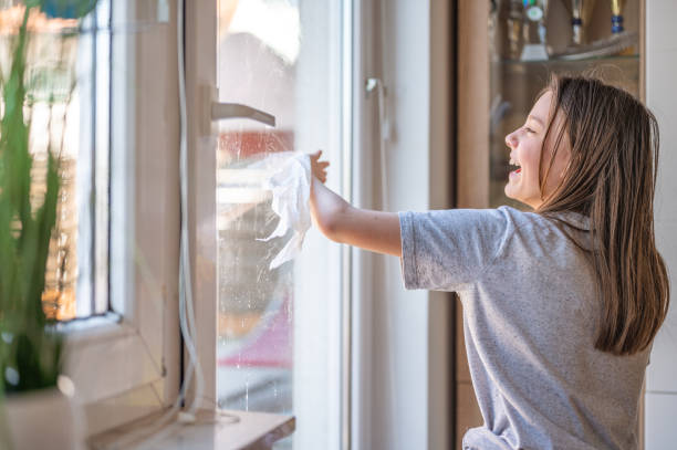 istock Young girl cleaning window at home 1217463476