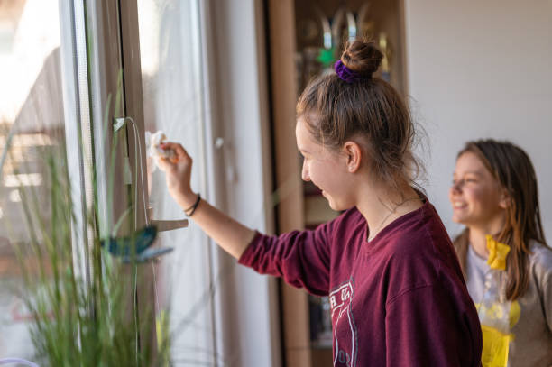 istock Two young girls cleaning window at home 1217463527