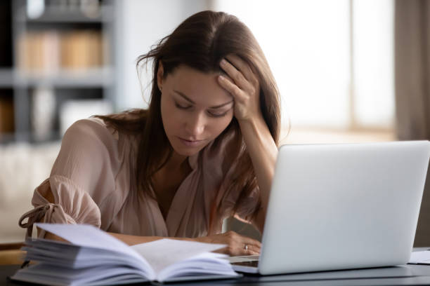 istock Head shot exhausted female student holding head in hand. 1217463768