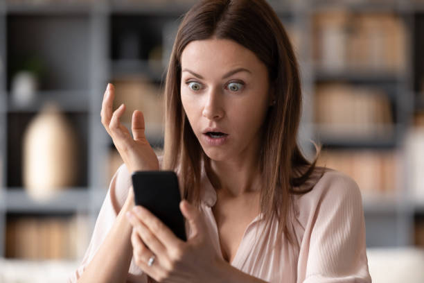 Close up young shocked woman looking at mobile phone screen. Head shot close up young shocked woman looking at mobile phone screen, received bank debt notification. Stunned frustrated lady reading sms with unbelievable news on smartphone, making big eyes. computer crime photos stock pictures, royalty-free photos & images