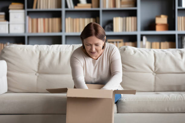 istock Pleasant middle aged woman unpacking cardboard box. 1217463862