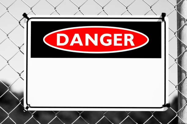 istock Red sign DANGER on chain link fence, black and white background with copy space 1217466543