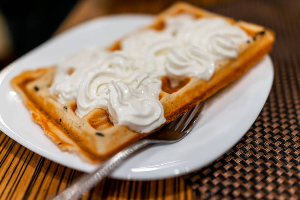 zbliżenie makro widok belgijski wafel na białym talerzu z widelcem zwieńczone bitą śmietaną w porannej kawiarni śniadaniowej w polsce podczas bożego narodzenia zimą - 18801 zdjęcia i obrazy z banku zdjęć