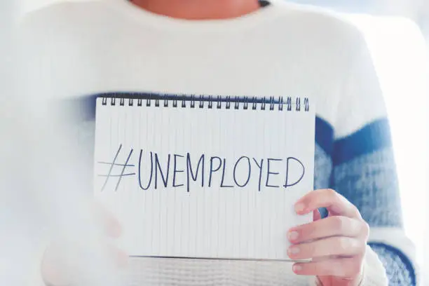 Woman holding a #unemployed sign written on a pad. Human resources, recession or economic depression concept