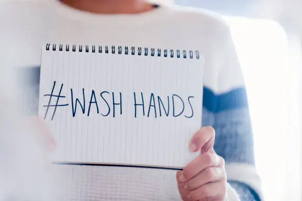 Woman holding a #washhands sign. This is to illustrate the Coronavirus hand washing hygiene concept. Copy space