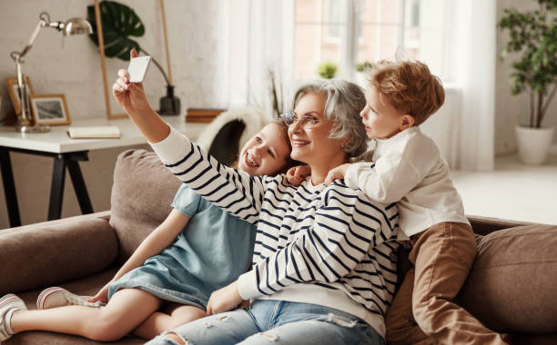 grandmother taking selfie with grandchildren - wireless technology cheerful granddaughter grandmother imagens e fotografias de stock