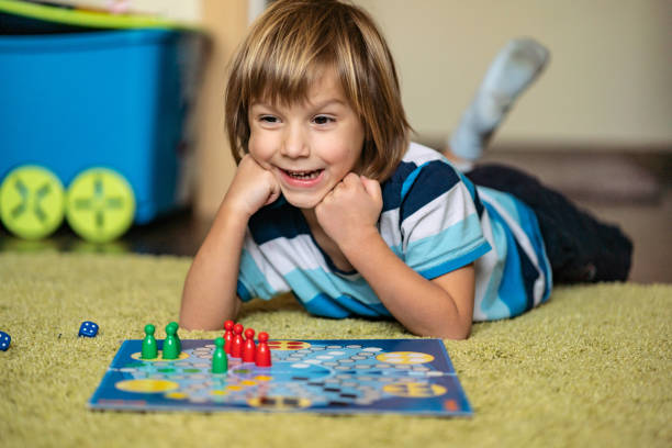 istock Smiling boy is lying on the floor and plays board game 1217473563