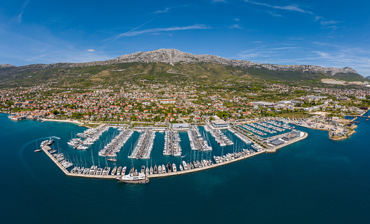 Croatia, marina Kastela, 15 September 2019: Drone view point on moored in an equal row sailboats, participant of a sailing regatta, piers, a lot of boats, mountains is on background