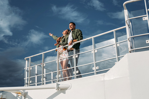 Beautiful cheerful young couple enjoying their ride on a cruise ship deck.