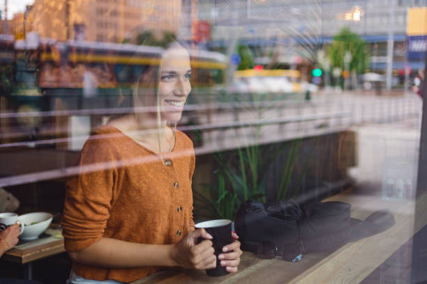 istock Beautiful woman enjoying coffee at a cafe while looking through a window 1217476379