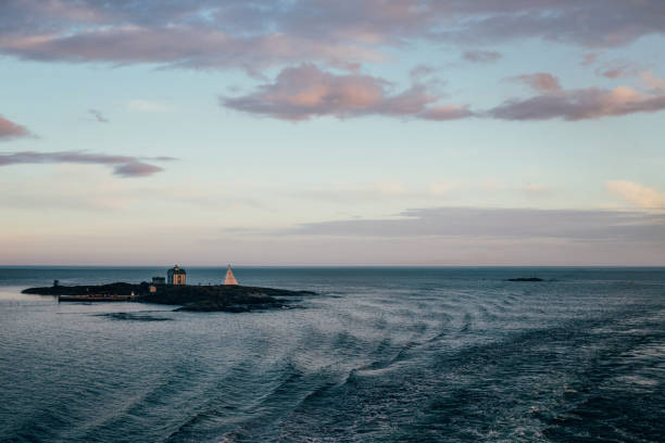 Morning at sea with waving tides, a lighthouse and some small islands