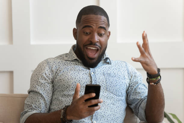 istock African guy open mouth looking at smartphone screen feels amazement 1217477768