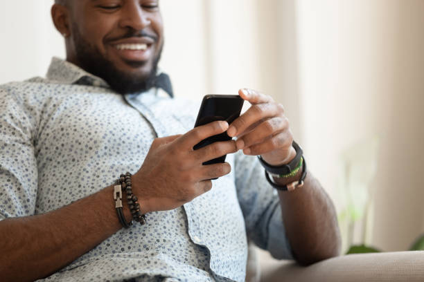 istock Guy sitting on couch closeup focus on hands holding smartphone 1217477772