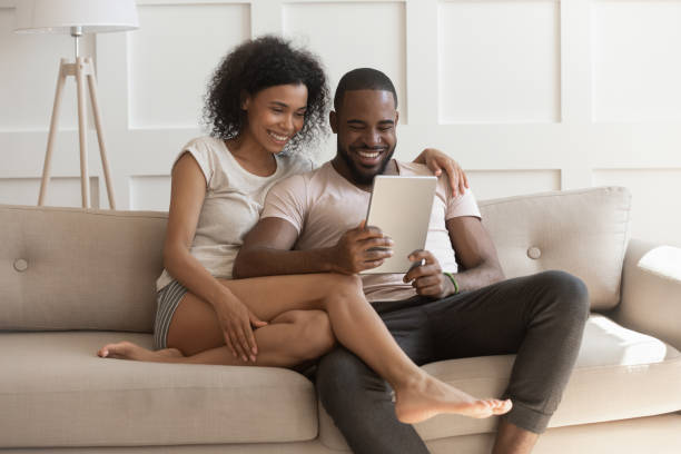 istock African beautiful couple resting on couch with tablet computer 1217477806