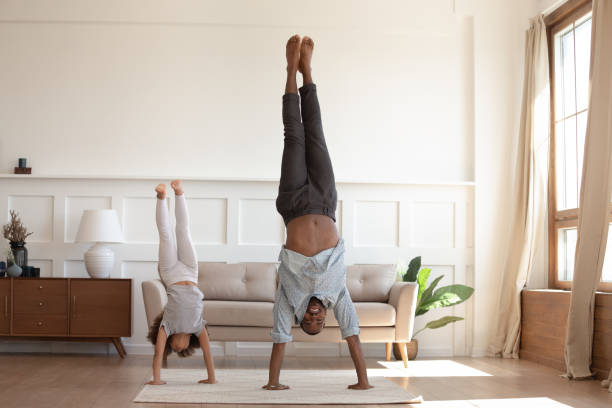 African father and daughter stand on hands heads down position