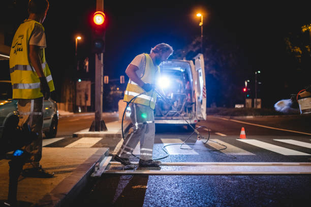 istock Road Worker Spray Painting Road Surface Marking at Night 1217480453