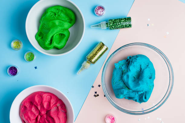istock Homemade plasticine, plasticine, play dough on a colored background with glitters. Molding clay or slime. Homemade clay. 1217480909