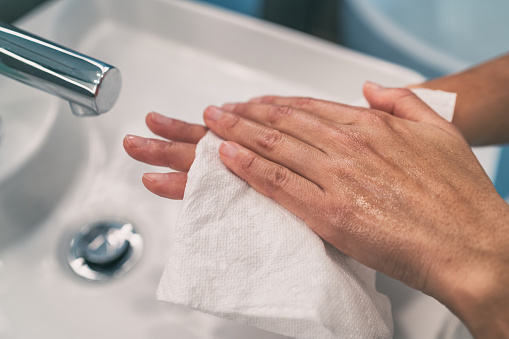 Washing hands steps for personal hygiene COVID-19 prevention drying hand with paper towel after handwash. Coronavirus infection preventive cleaning