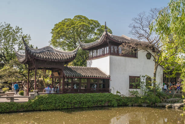Double eatery building at Humble Administrators garden, Suzhou, China. Suzhou China - May 3, 2010: Humble Administrators Garden. Double traditionally built eatery building at pond with set in green environment under blue sky. People present. suzhou creek stock pictures, royalty-free photos & images