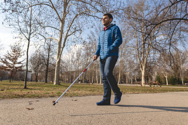 istock Independent young man walking with a blind persons cane at a park 1217483248