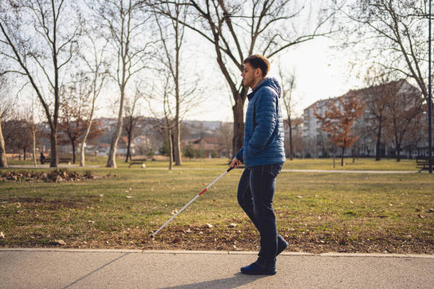 istock Young blind person enjoying a walk at a park with a blind persons cane 1217483817