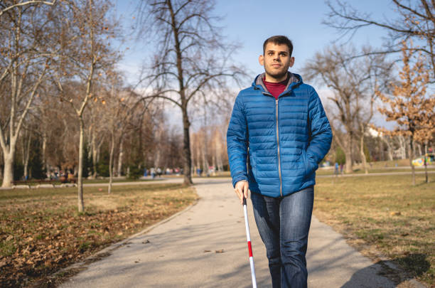 istock Young man with a visual disability walking with an assistance of a blind persons cane 1217483848