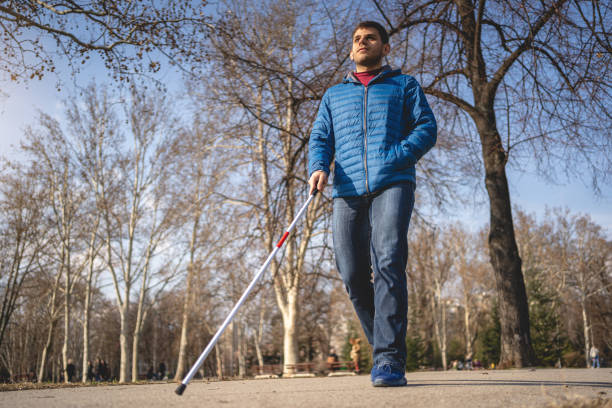 istock Young blind person with a visual disability walking with a cane at a park 1217483982