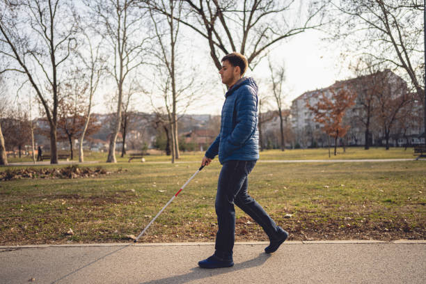 istock Young man with a visual impairment walking with a cane 1217484013