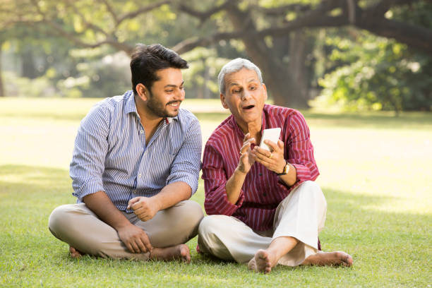 father and adult son relaxing in park stock photo - old men asian ethnicity indian culture imagens e fotografias de stock