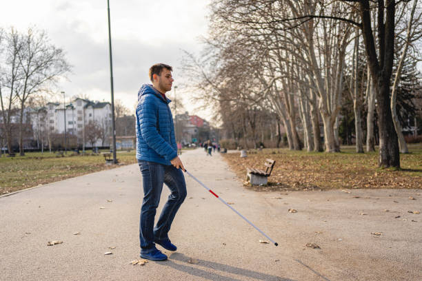 istock Young blind person enjoying a walk at a park with a blind persons cane 1217484059