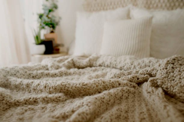 Letto matrimoniale stratificato con piumino neutro e comode coperte da lancio - foto stock