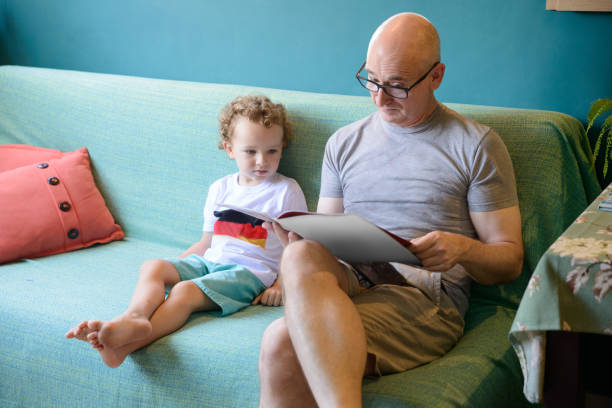 istock Curious toddler reading book bonding with uncle 1217500357