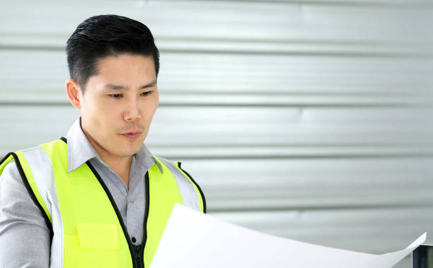 istock Engineer man standing in the office and look information on blueprint paper. 1217504654