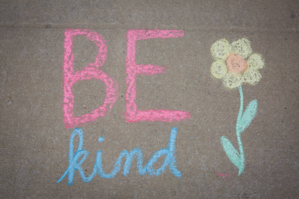 istock Be Kind words and a flower drawn with sidewalk chalk - temporary art 1217510377