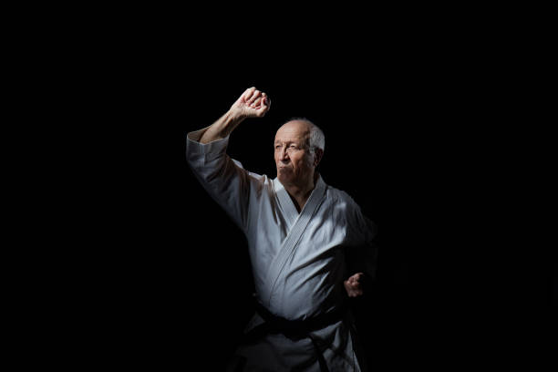 istock An old male athlete is training a block with his hand at an average level on a black background 1217515472