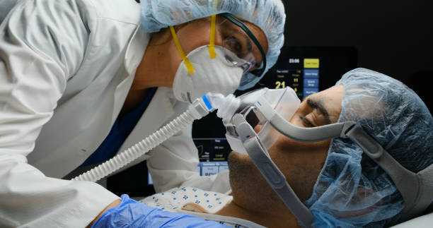 Female doctor checking on Covid-19 infected patient while connected to a ventilator Female caucasian doctor checking on Covid-19 infected patient while connected to a ventilator at a hospital room mediterranean ethnicity stock pictures, royalty-free photos & images