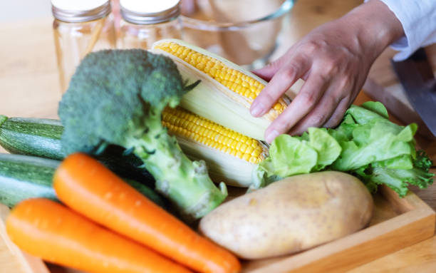 istock A woman chef holding and picking a fresh corn from a vegetables tray 1217519593