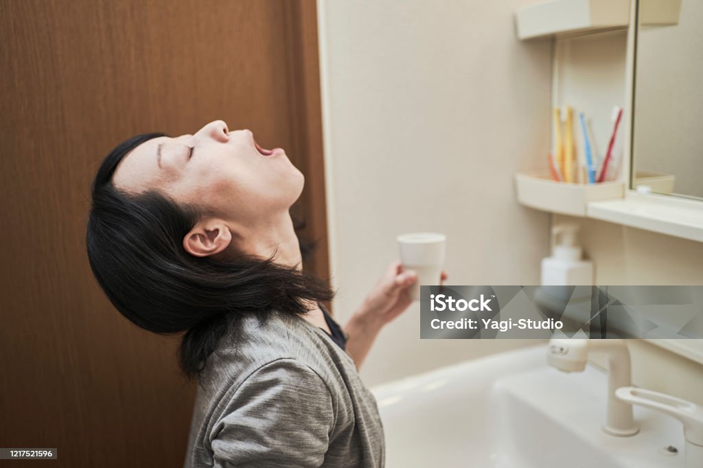 Women gargle with antivirus Woman gargle in the washroom Mouthwash Stock Photo