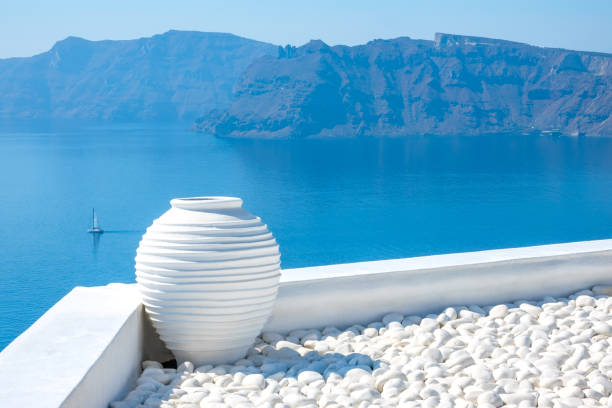Greece. Sunny day on Santorini. White pebbles and a stone vase. Seascape with rocky islands