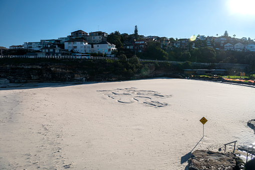Stay Home sign drawn into the  sand at the closed Tamarama Beach, Sydney Australia
