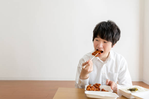 uomo d'affari asiatico che lavora da casa godendosi il pasto da asporto a casa - deep fried people fried chicken foto e immagini stock