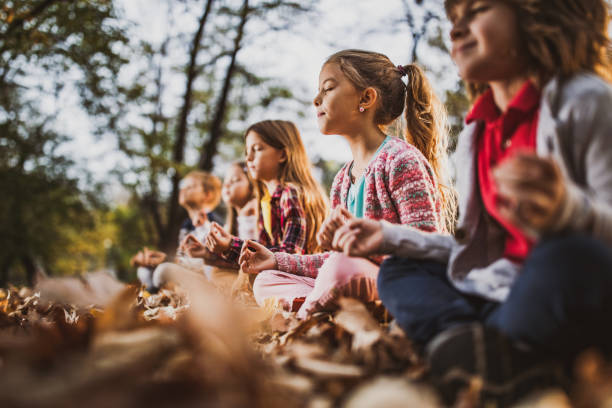 kleine kinder, die yoga-entspannungsübungen am herbsttag machen. - zen like nature breathing exercise sitting stock-fotos und bilder