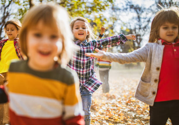 istock Playful children having fun while running in autumn day at the park. 1217527537