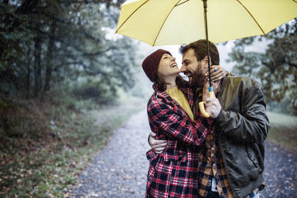 istock Cheerful embraced couple taking a walk on a rainy day at forest. 1217528696