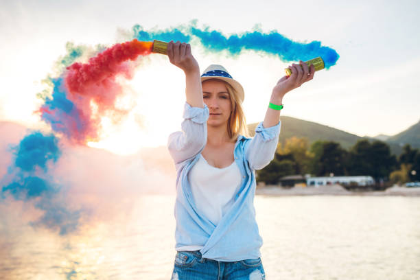 istock Woman having fun with smoke bomb on the beach 1217528957