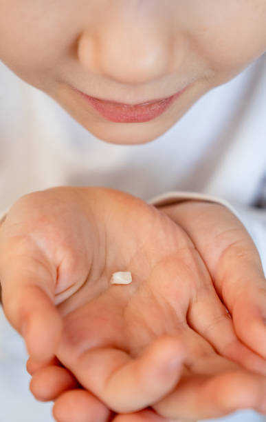 istock kid girl with fallen milk tooth in hand. 1217531173