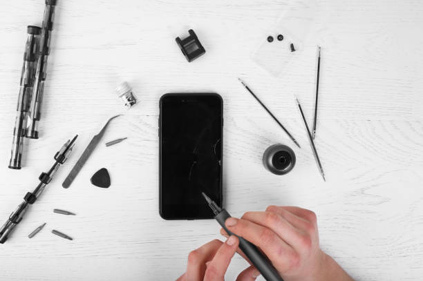 istock Repairman workplace with phone and special tools. Disassembled smartphone with disassembling instruments and repairer hands on white background. Electronics repair service, device production concept 1217533460