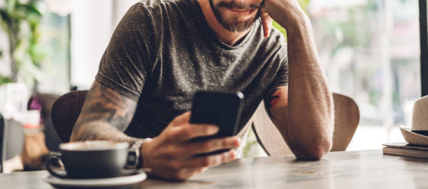 istock Handsome bearded hipster man use smartphone with coffee at table in cafe.Communication and technology concept 1217534573